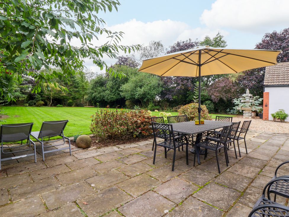 A garden with a dining table and umbrellas at Millstone Cottage Leven Near Beverley