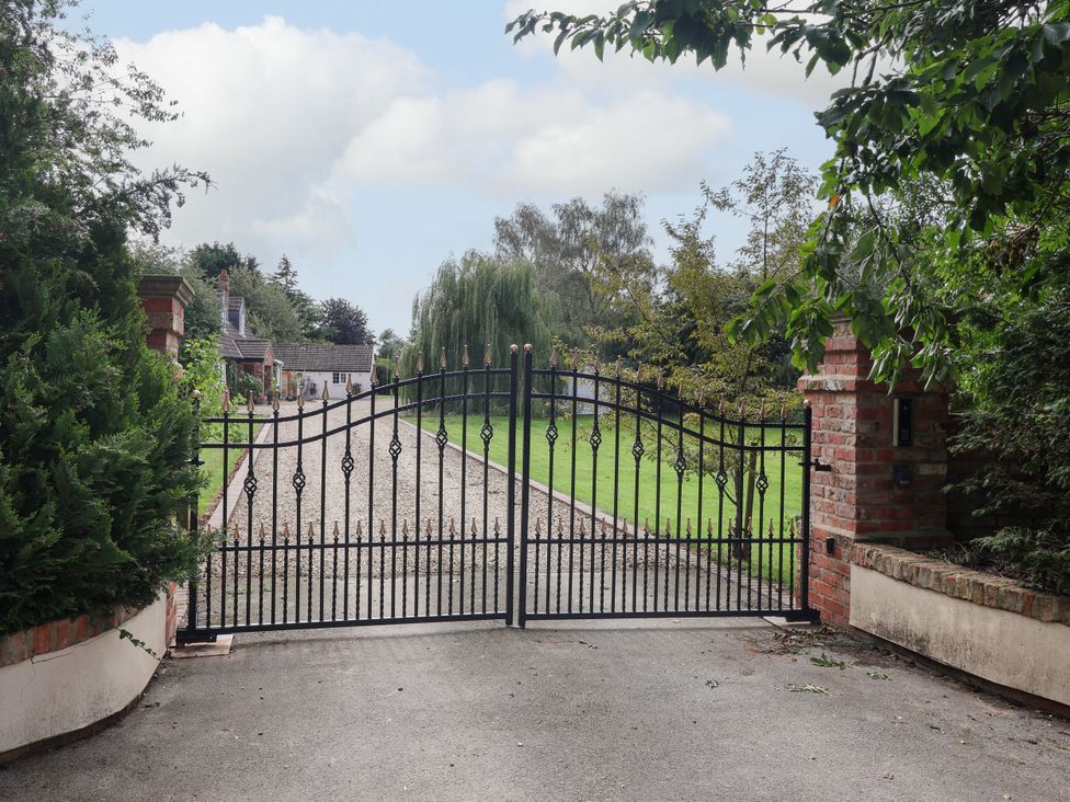 A gate leading to a gravel driveway at Millstone Cottage Leven Near Beverley