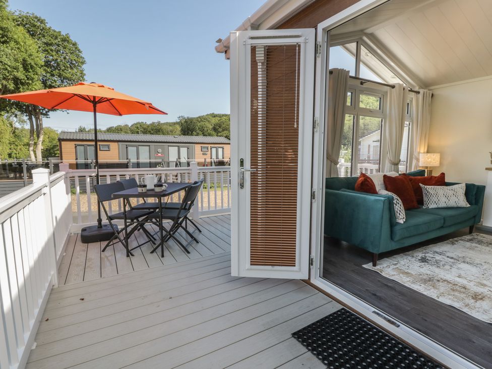 A deck with a table and chairs beside a sofa at 73 Cildraeth in New Quay