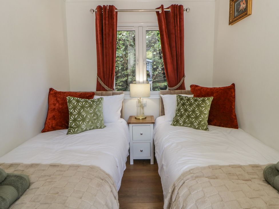 A bedroom with two beds and a lamp on a nightstand at 73 Cildraeth in New Quay