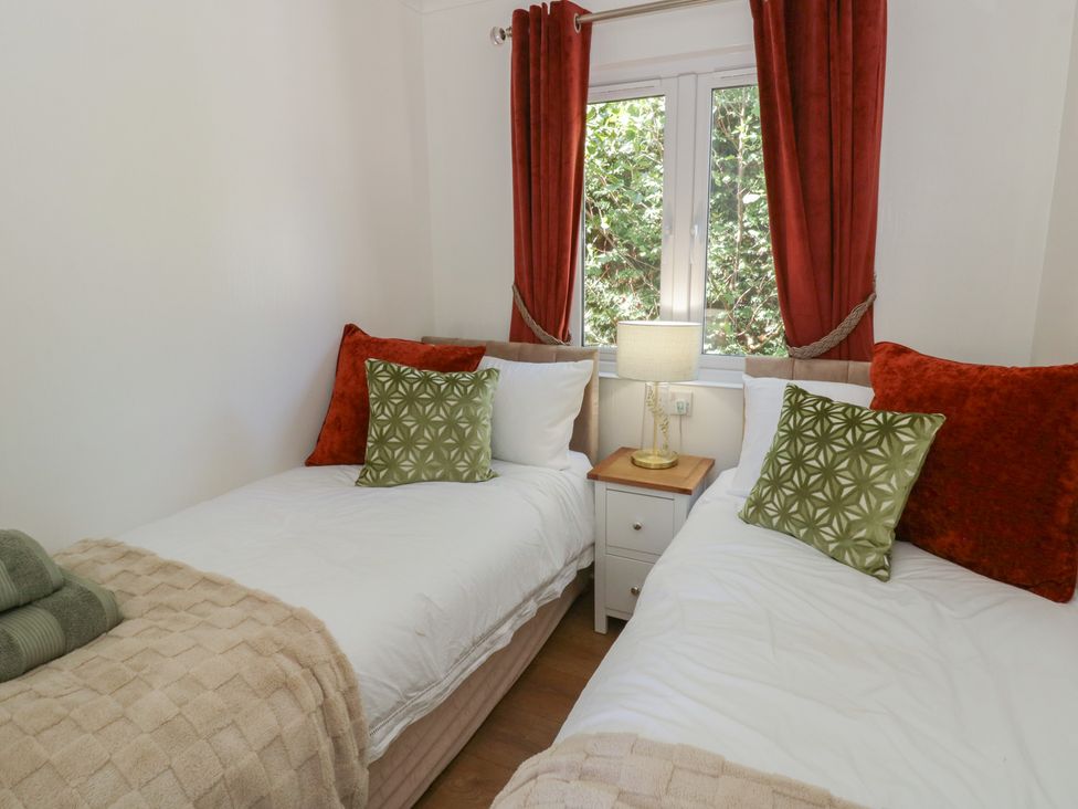 A bedroom with two beds and a bedside table at 73 Cildraeth in New Quay