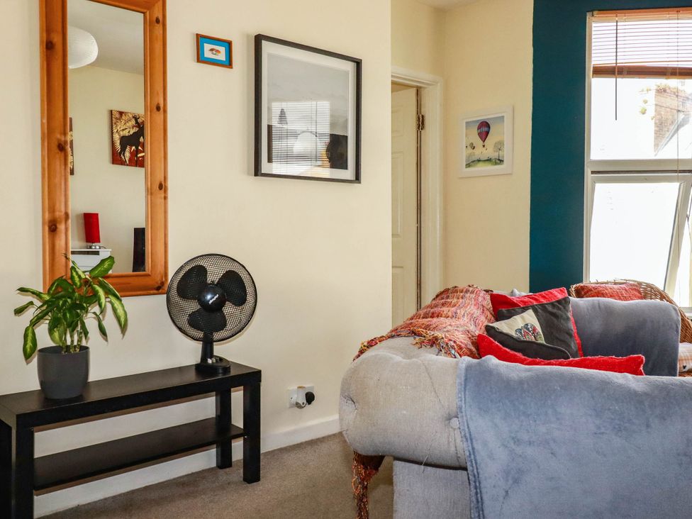 A living room with a mirror, fan, and couch at Seaside Retreat in Newquay