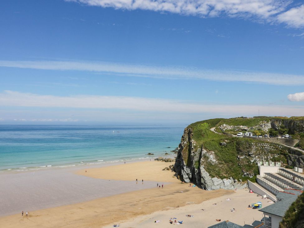 A beach with people on the sand and cliffs at Seaside Retreat in Newquay