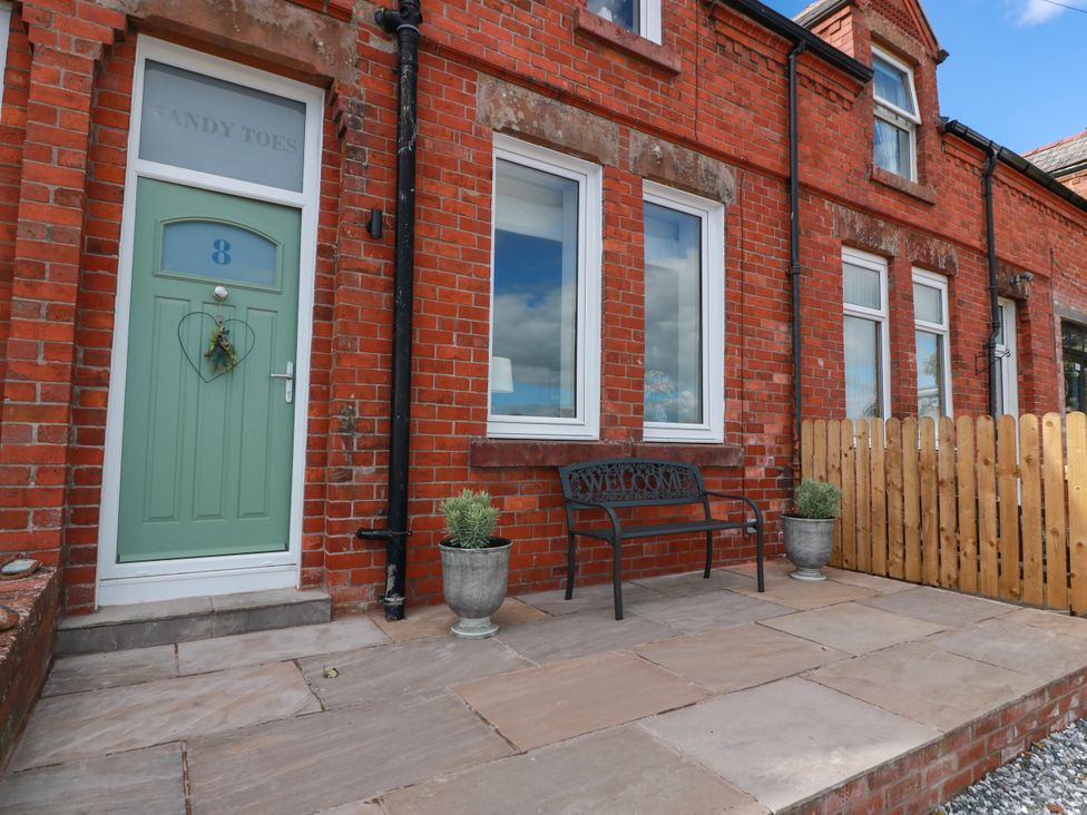 An outdoor area with a front door and bench at Sandy Toes in Powfoot, Annan