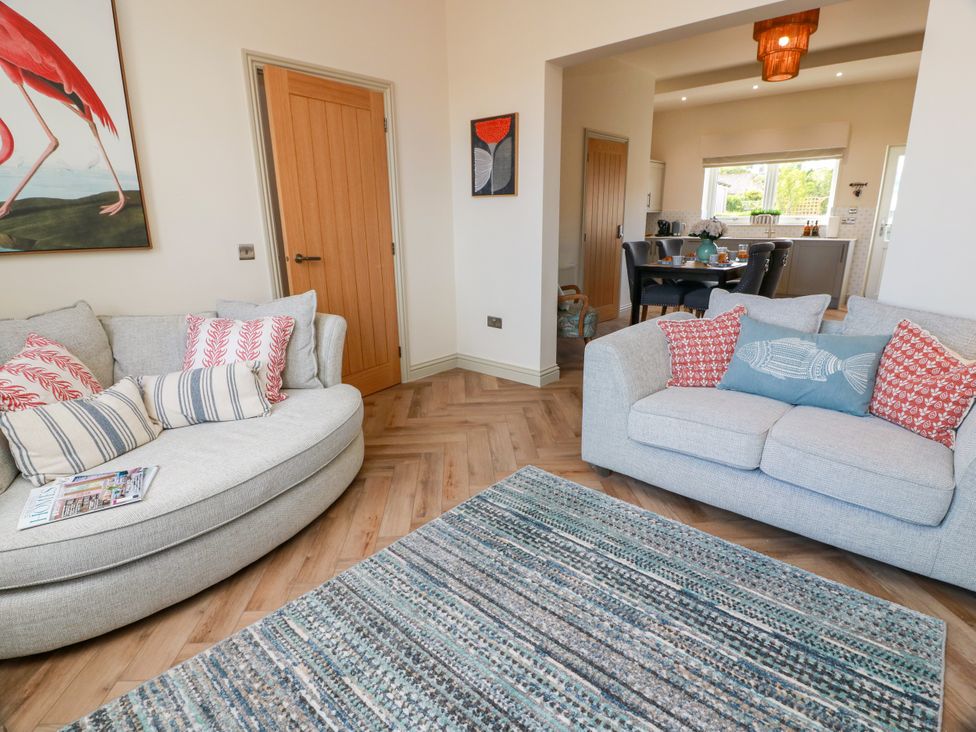 A living room with sofas and a dining area at Sandy Toes in Powfoot, Annan