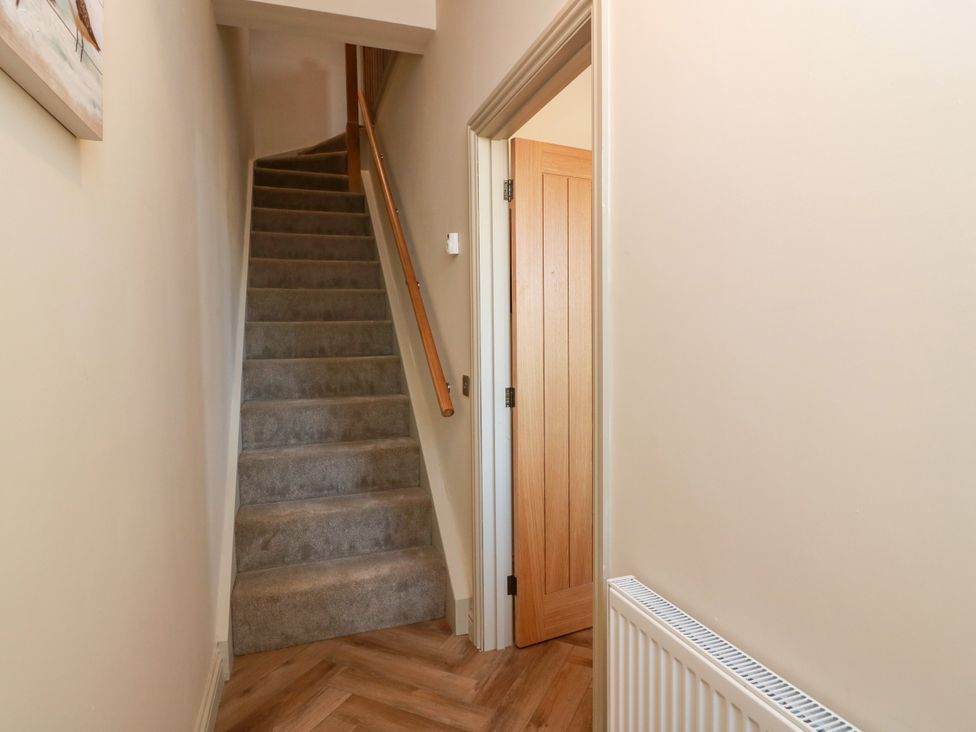 A hallway with stairs leading up and a door to a room at Sandy Toes, Powfoot, Annan