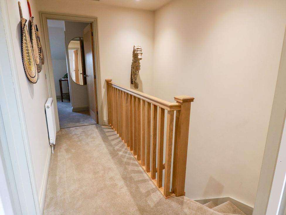 A hallway with a staircase and handrail at Sandy Toes in Powfoot, Annan