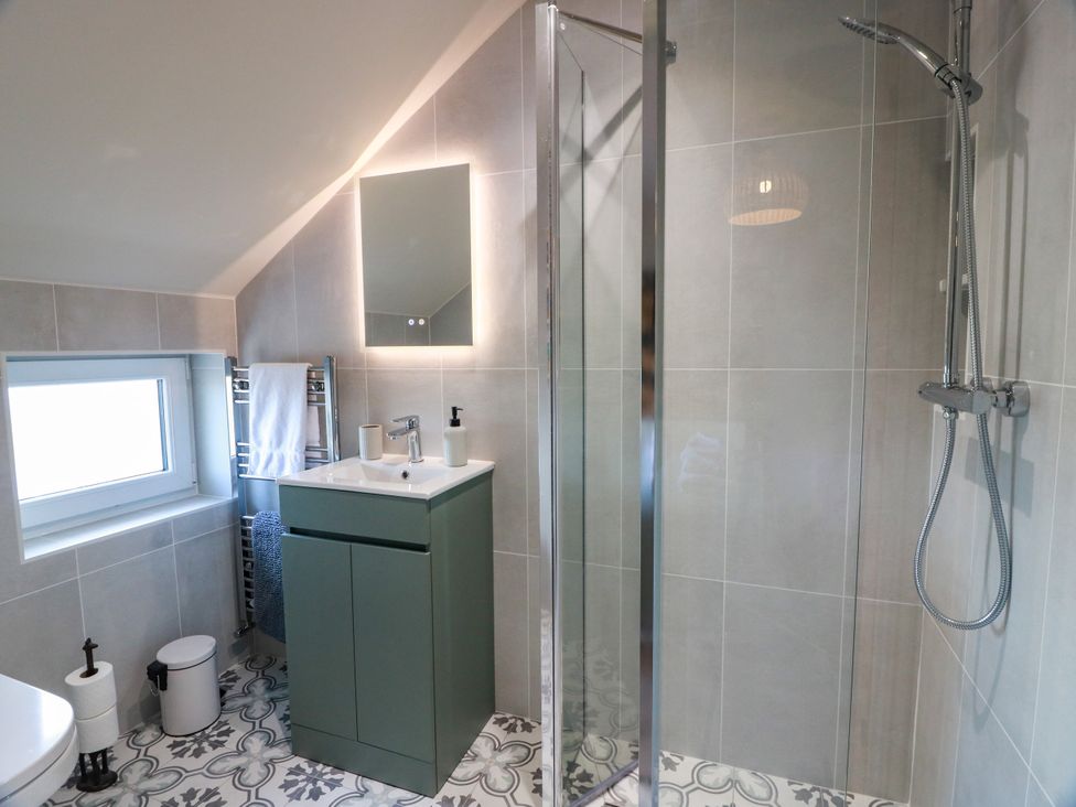 A bathroom with shower, sink and towel rack at Sandy Toes in Powfoot, Annan