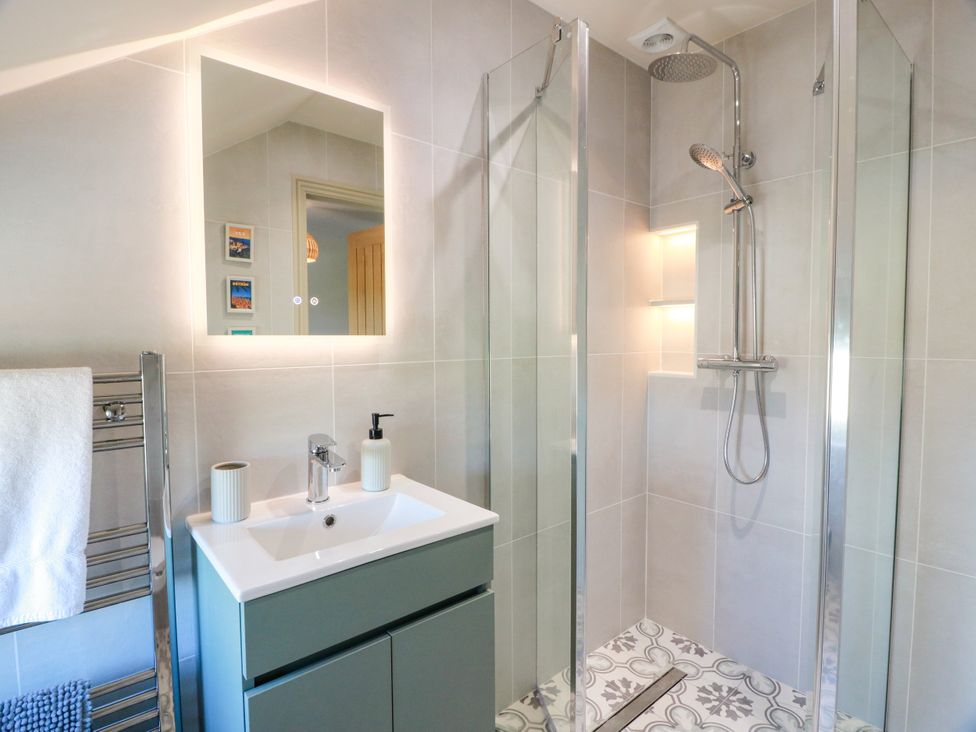 A bathroom with a shower and sink area at Sandy Toes in Powfoot, Annan