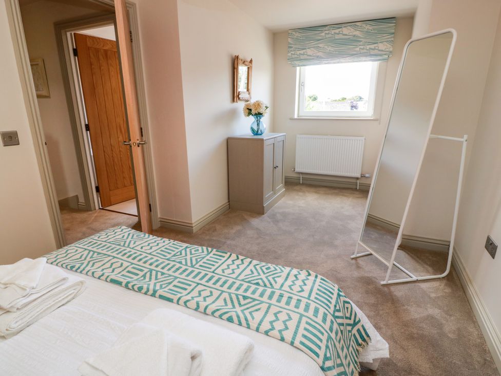 A bedroom with a dresser and a mirror at Sandy Toes in Powfoot, Annan