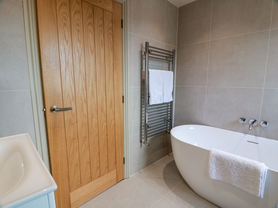 A bathroom with a bathtub and towel rail at Sandy Toes in Powfoot, Annan