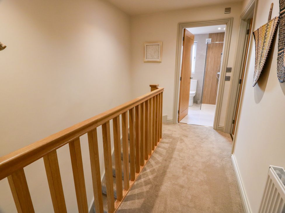 A hallway with a staircase and a doorway leading to a bathroom at Sandy Toes, Powfoot, Annan