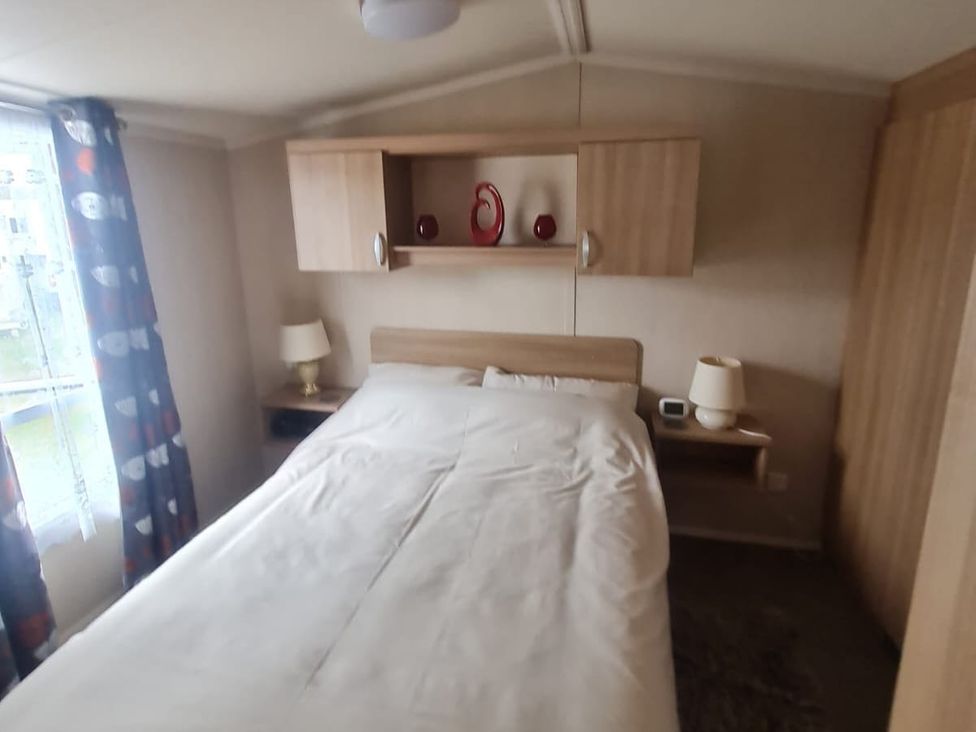 A bedroom with a bed and bedside lamps at Stoup cross caravan park in Whitby