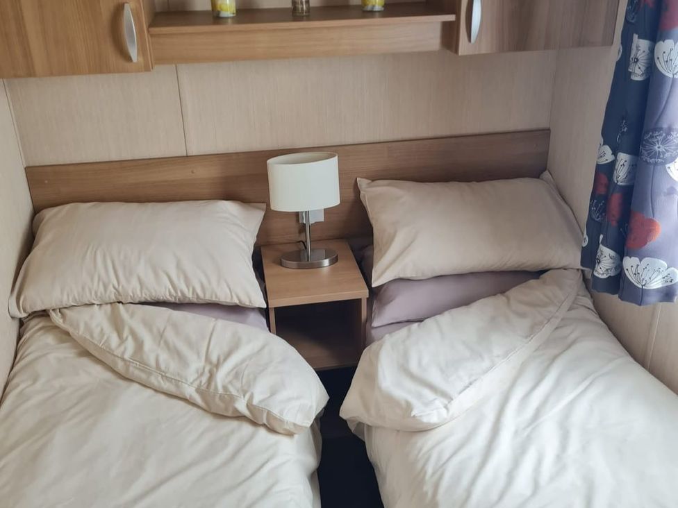 A bedroom with two beds and a nightstand at Stoup cross caravan park, Whitby