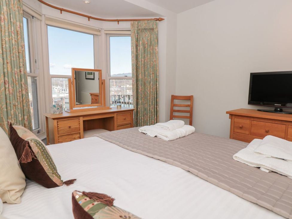 A bedroom with a bed, mirror, television, and curtains at 33 Dart Marina in Dartmouth