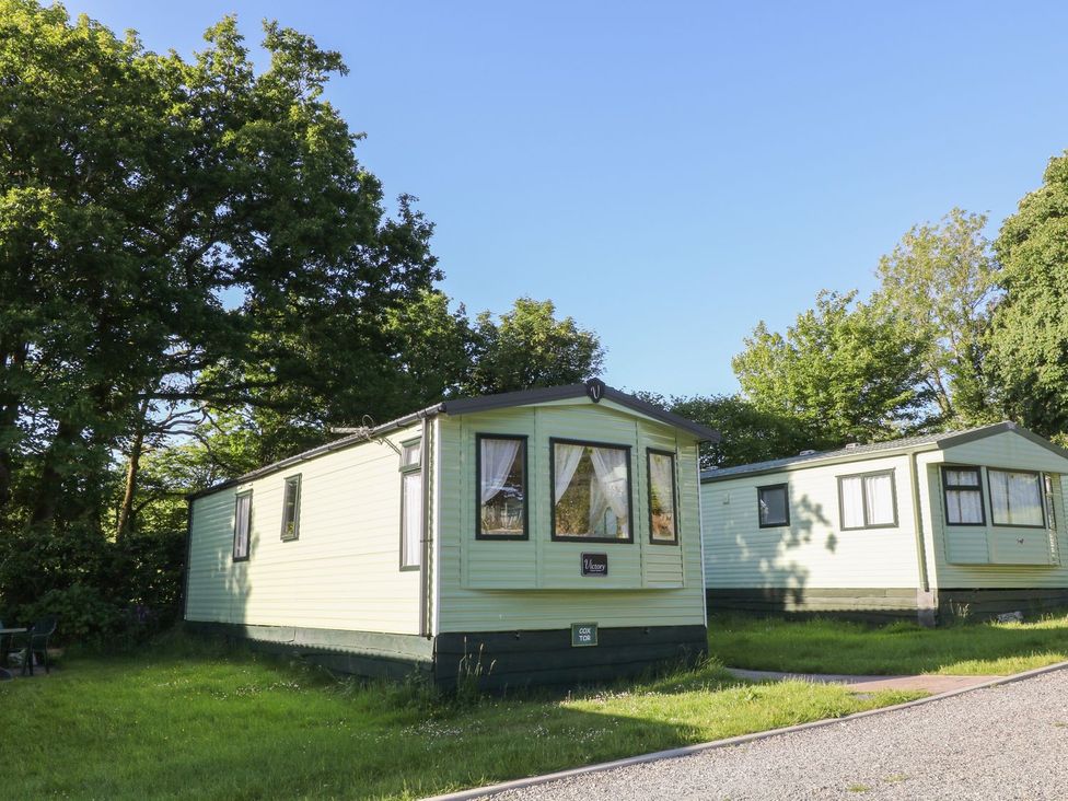 A static caravan with green exterior and windows outside at Cox Tor in Tavistock