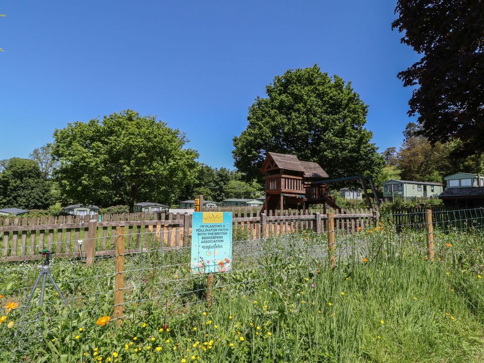 A playground with a sign and trees at Cox Tor in Tavistock