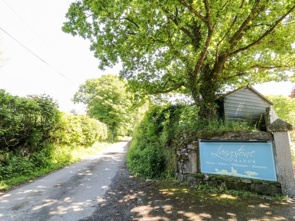 A road with a sign for Langstone Manor and trees in Tavistock
