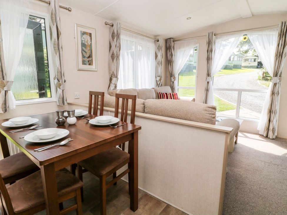 A living room with a dining area and windows at Roos Tor in Tavistock