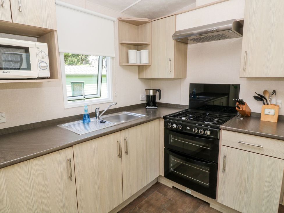 A kitchen with cabinets, a sink, and a gas stove at Roos Tor in Tavistock