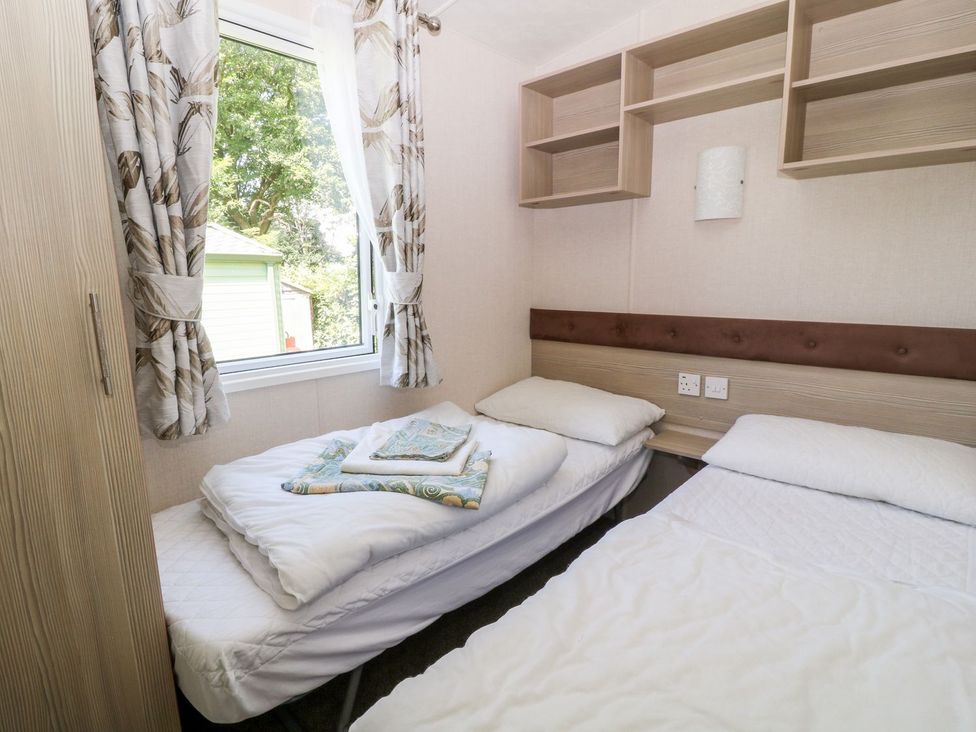 A bedroom with two beds and a wardrobe at Roos Tor in Tavistock