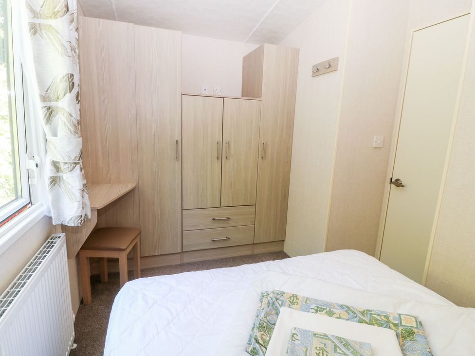 A bedroom with a wardrobe, desk, and chair at Roos Tor in Tavistock