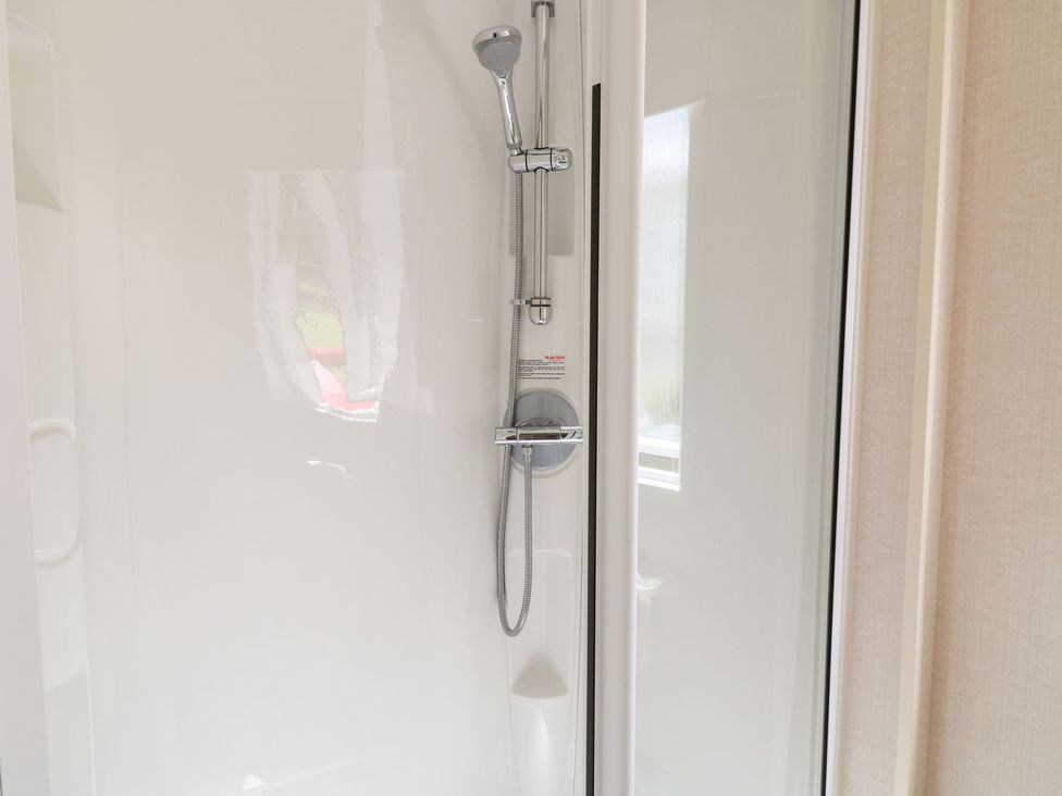 A shower with a showerhead and glass door at Roos Tor in Tavistock