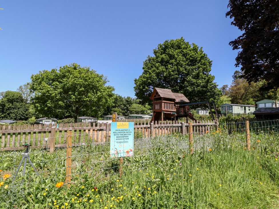 A playground with a treehouse and sign at Roos Tor Tavistock