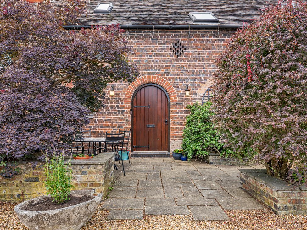 An outdoor area with a table and chairs in front of a brick wall at Oxhay Barn Newcastle