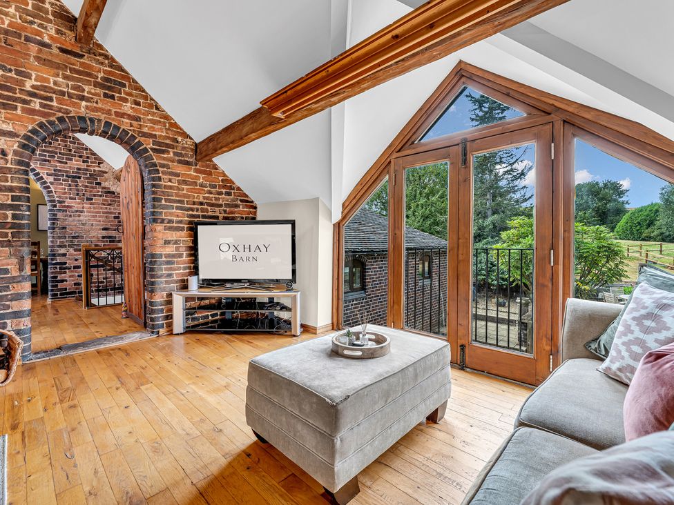 A living room with a television and a view of the outdoor area at Oxhay Barn Newcastle