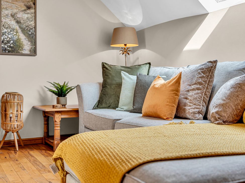 A living room with a sofa, cushions, and a lamp at Oxhay Barn in Newcastle