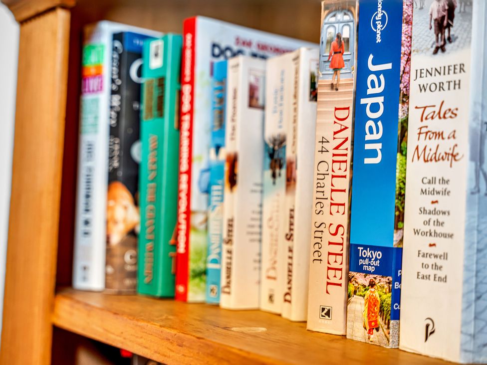 A shelf with various books in a living room at Oxhay Barn Newcastle