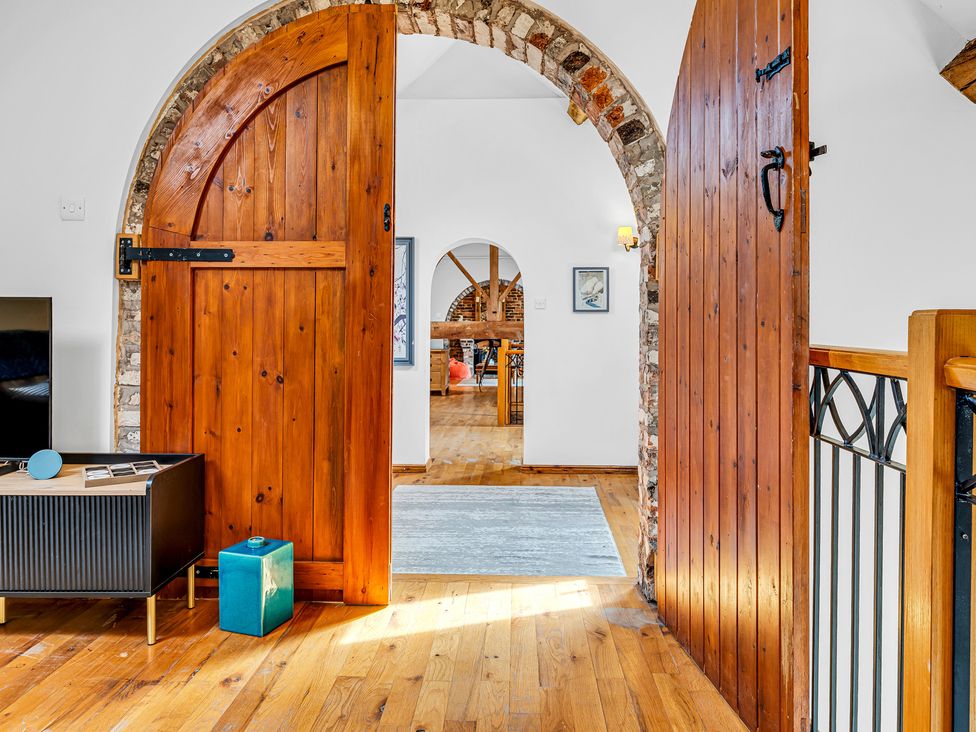 A living room with wooden doors and a television at Oxhay Barn Newcastle