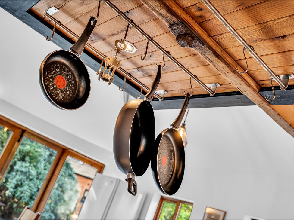 A kitchen with frying pans hanging from a suspension rack at Oxhay Barn Newcastle