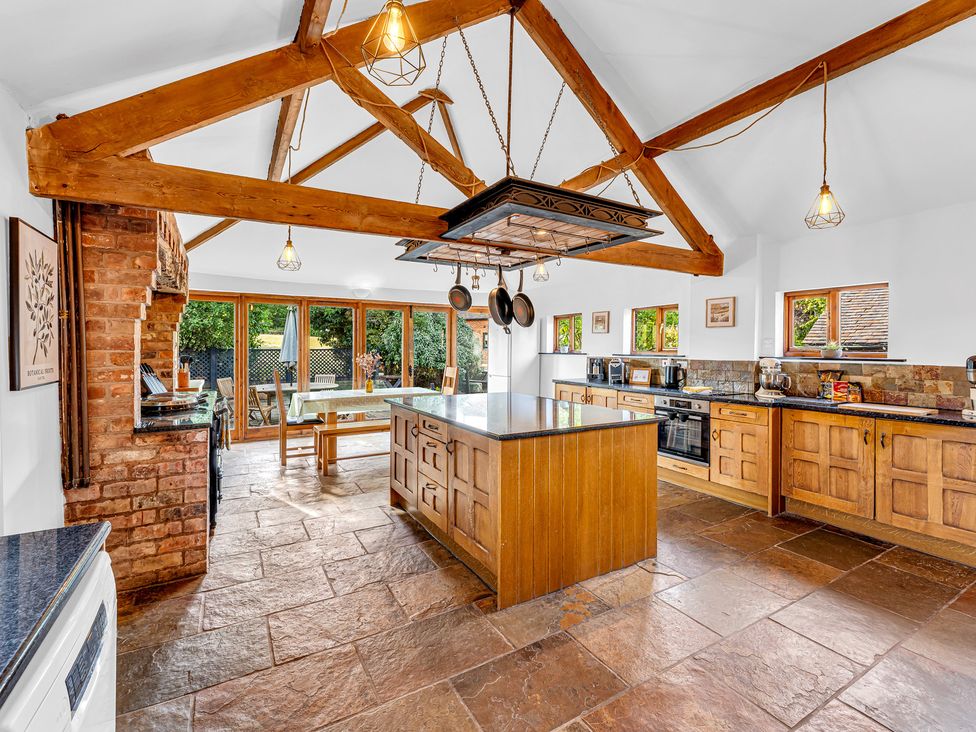 A kitchen with an island, cabinets, and windows at Oxhay Barn Newcastle