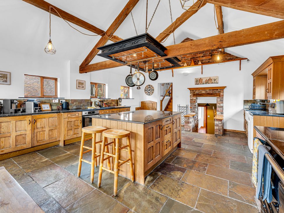A kitchen with wooden cabinets and stone flooring at Oxhay Barn Newcastle