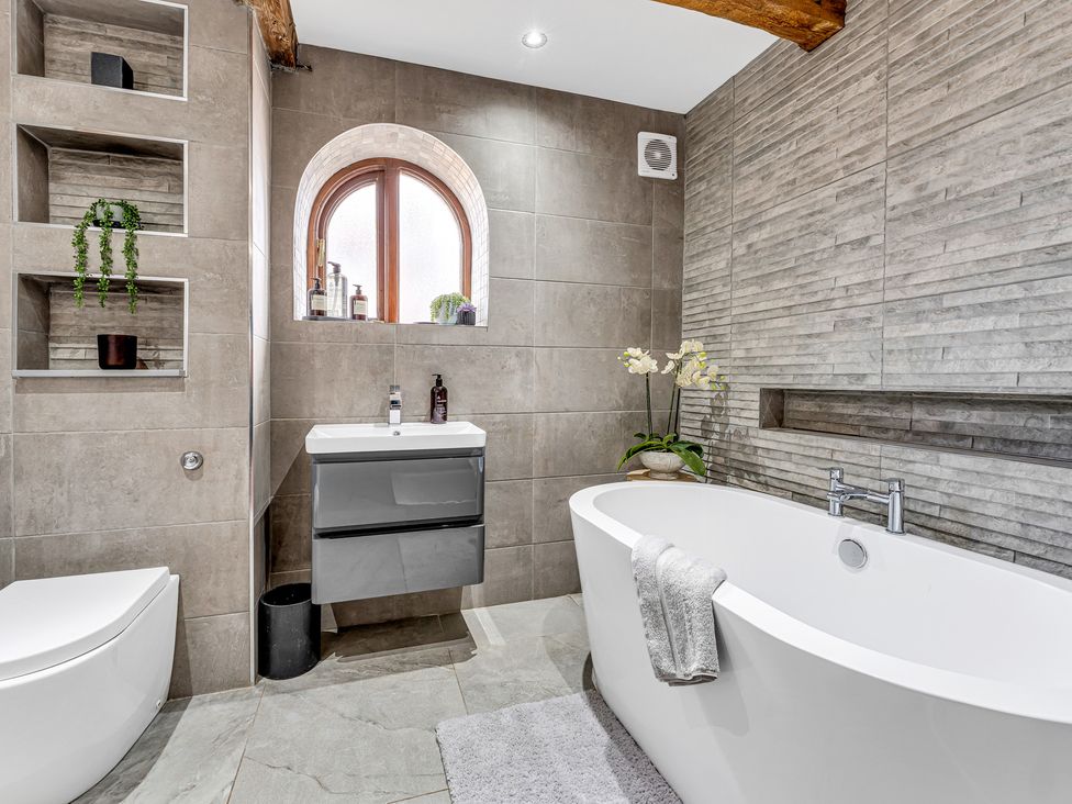 A bathroom featuring a bathtub, toilet, and sink at Oxhay Barn Newcastle
