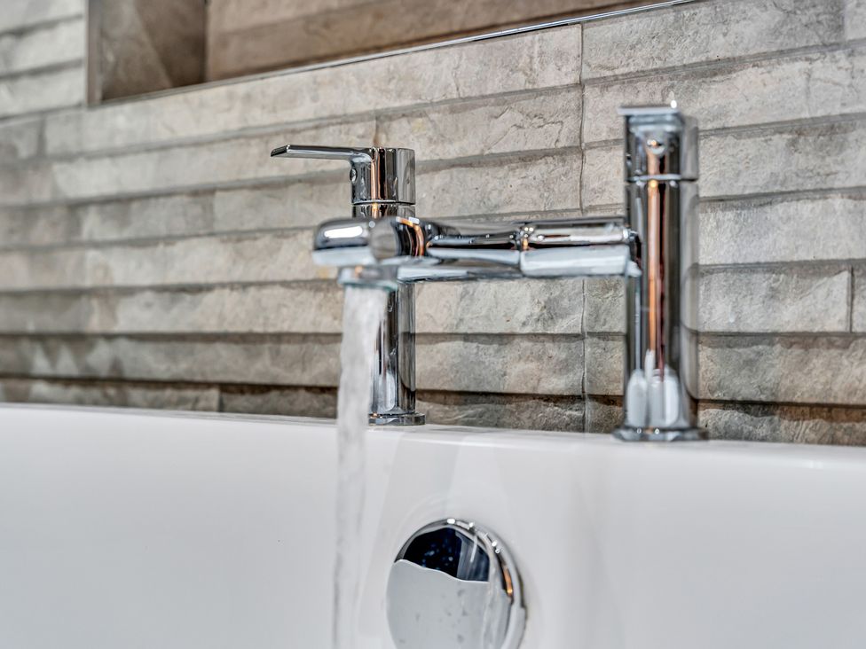 A faucet with running water above a bathtub at Oxhay Barn Newcastle