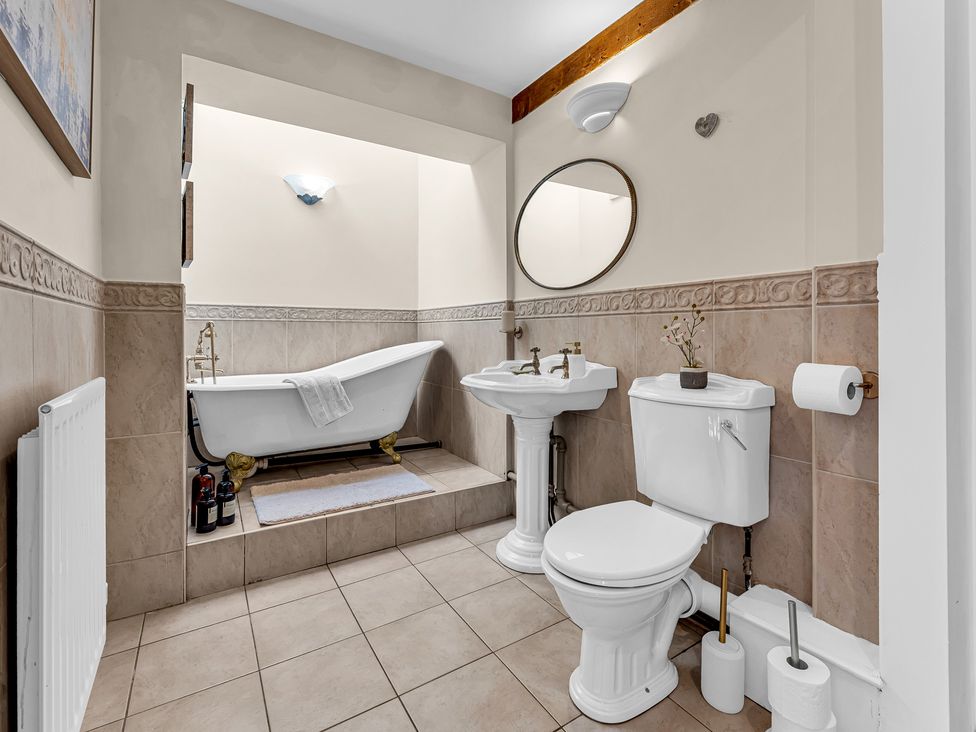 A bathroom with a bathtub, sink, and toilet at Oxhay Barn, Newcastle
