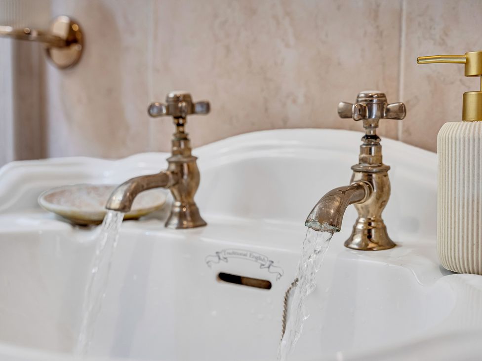 A sink with two faucets and water flowing at Oxhay Barn Newcastle