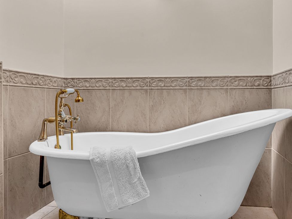 A bathroom with a bathtub and faucet at Oxhay Barn Newcastle