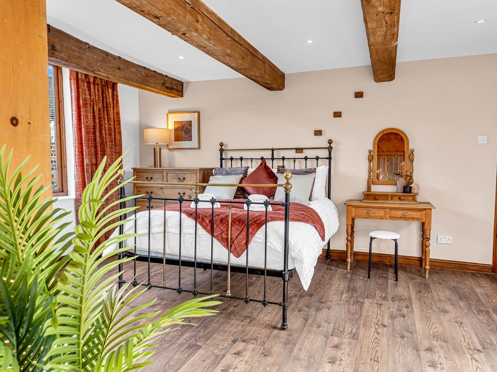 A bedroom with a bed, dressing table, and window at Oxhay Barn Newcastle