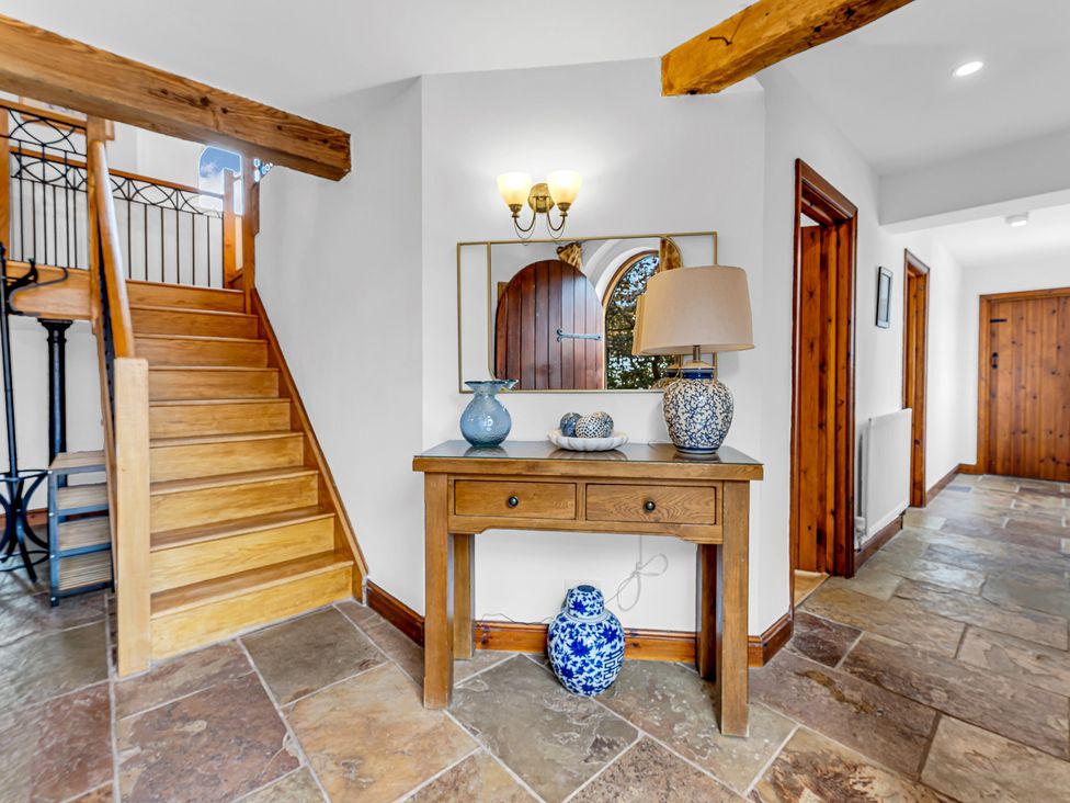 A hallway with a stairs and a console table at Oxhay Barn Newcastle