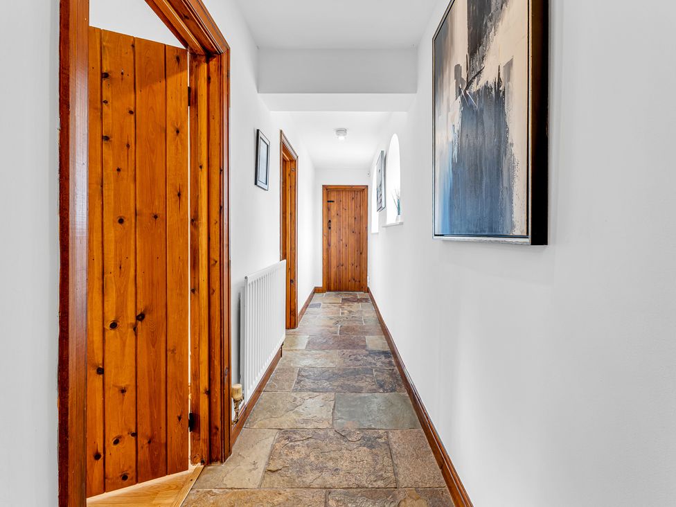 A hallway with wood doors and artwork at Oxhay Barn Newcastle