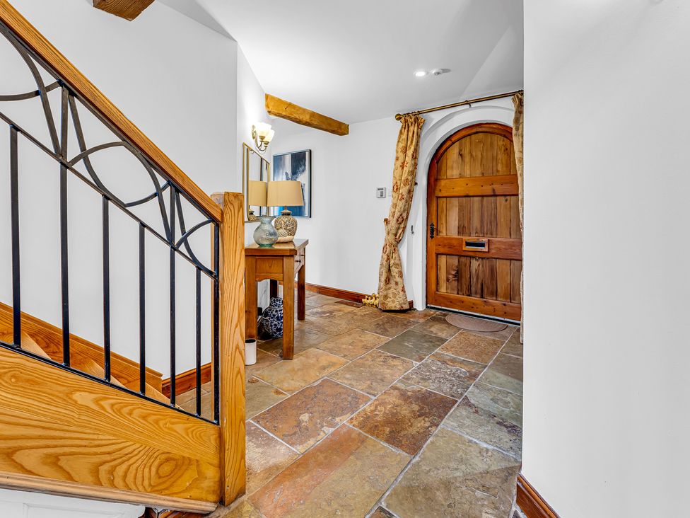 An entryway with a staircase and wooden front door at Oxhay Barn Newcastle