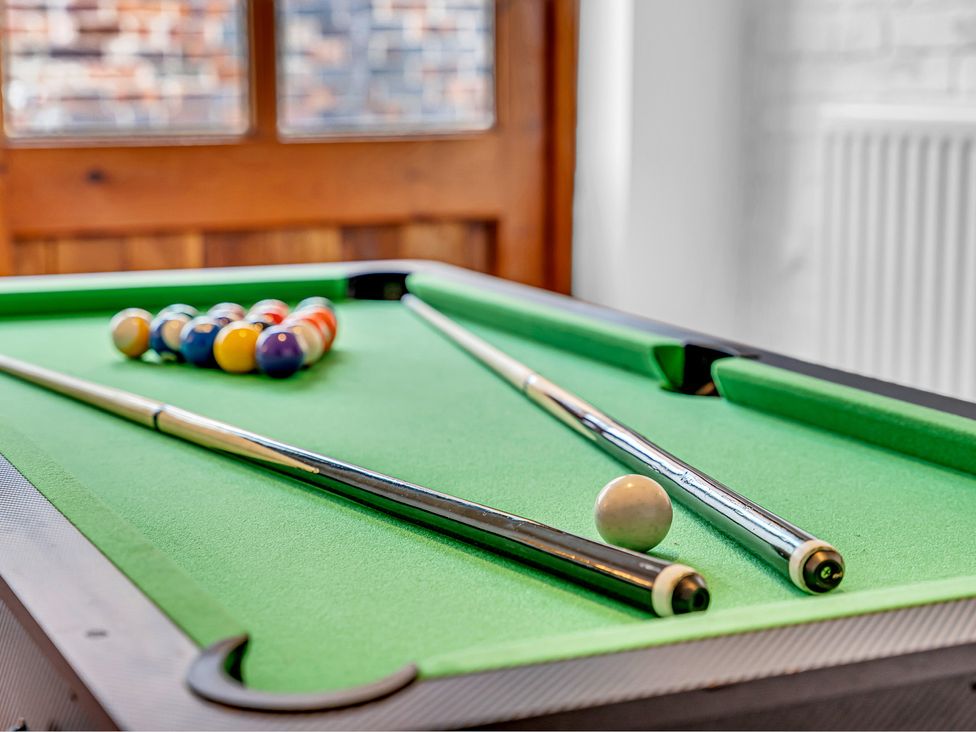 A pool table with balls and cue sticks at Oxhay Barn Newcastle