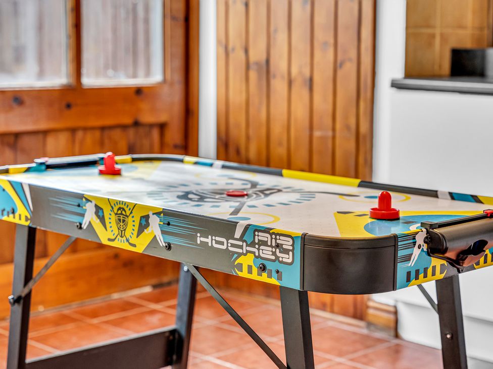 An air hockey table with red pucks in a game room at Oxhay Barn Newcastle