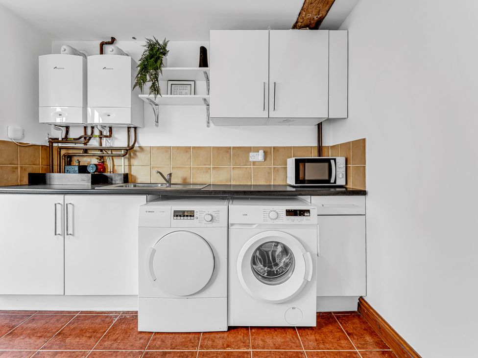 A laundry room with washing machine, dryer, sink and microwave at Oxhay Barn Newcastle