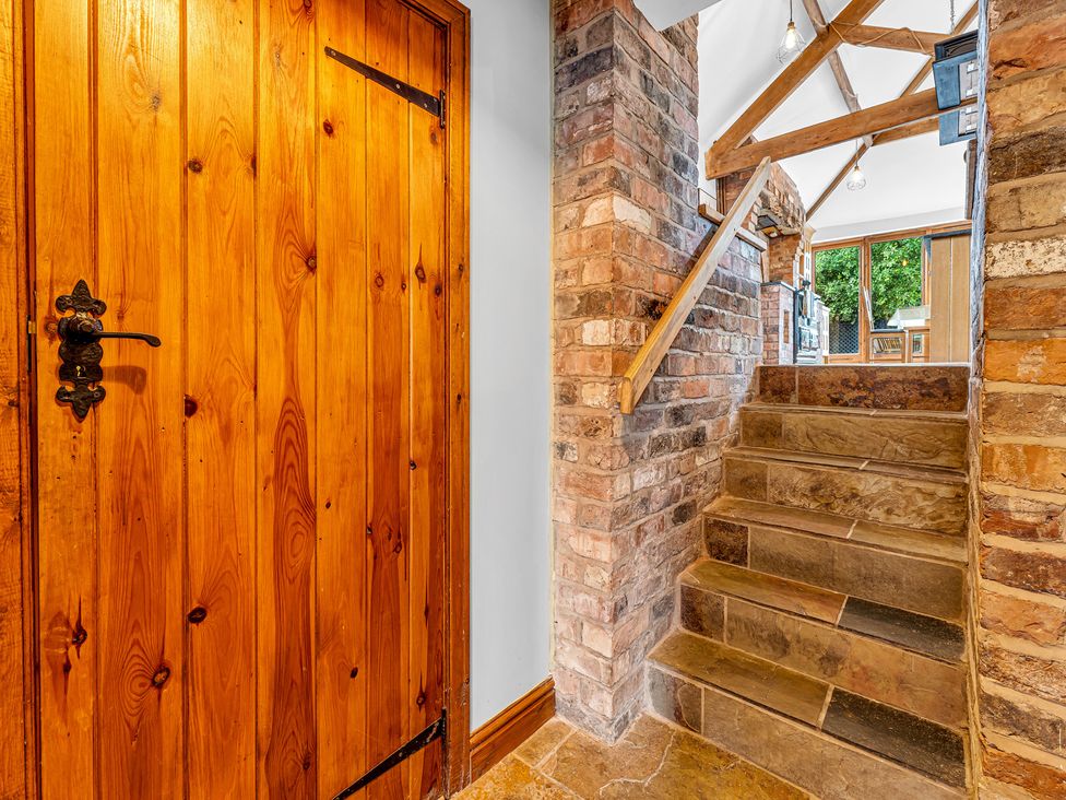 A hallway with a wooden door and staircase at Oxhay Barn Newcastle