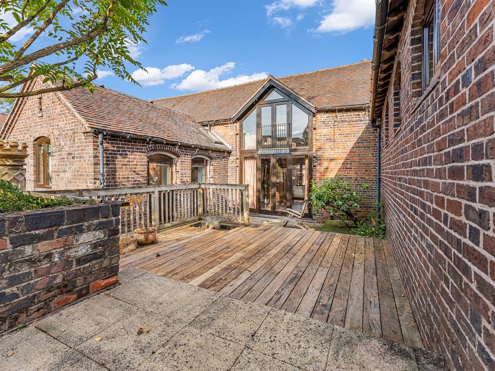 An outdoor area with wooden decking and a brick wall at Oxhay Barn Newcastle